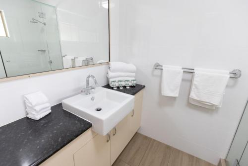 a white bathroom with a sink and a mirror at Sundowner Hotel Motel in Caboolture