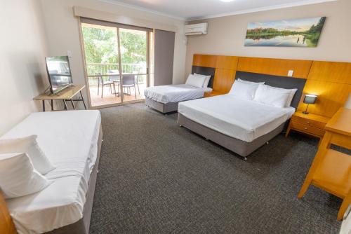 Habitación de hotel con 2 camas y balcón en Sundowner Hotel Motel, en Caboolture