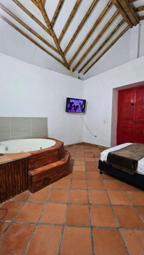 1 dormitorio con bañera, 1 cama y TV en HOSTERÍA BRISAS DEL RÍO, en Marinilla