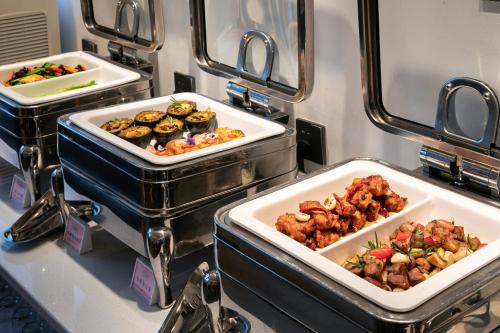 a buffet with three trays of food on a table at Changsha Zealandia Serviced Apartment in Changsha