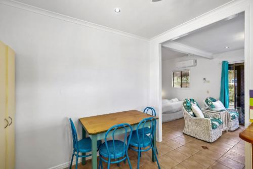 a dining room with a table and blue chairs at The Little Blue Shack - Quaint Granny Flat in Bli Bli