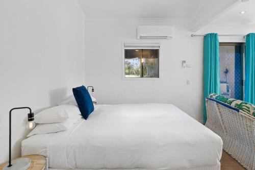 um quarto branco com uma cama e uma janela em The Little Blue Shack - Quaint Granny Flat em Bli Bli