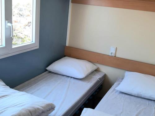 um pequeno quarto com 2 camas e uma janela em Mobil-Home Caves, 3 pièces, 4 personnes - FR-1-783-32 em Caves