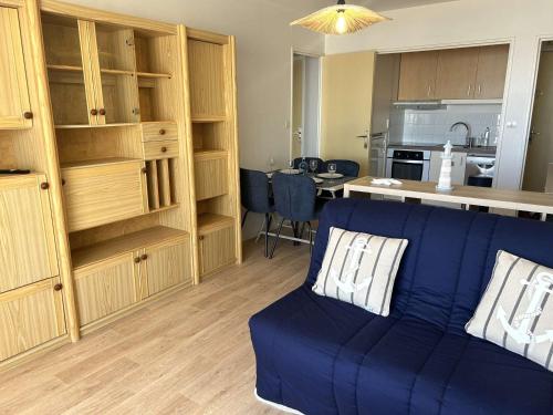 un salon avec un canapé bleu et une cuisine dans l'établissement Appartement 2 Pièces avec Vue Mer, Proche Plage et Parking à Saint-Gilles-Croix-de-Vie - FR-1-224-812, à Saint-Gilles-Croix-de-Vie