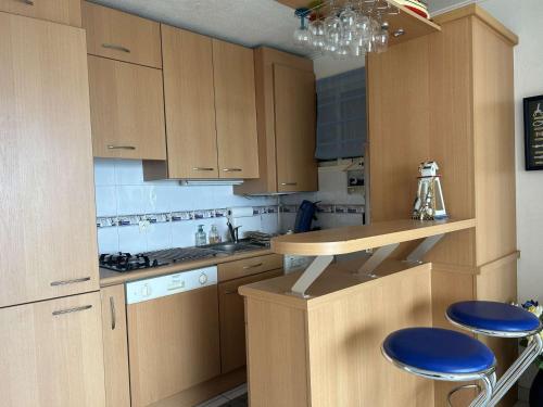 une cuisine avec des placards en bois et des tabourets bleus dans l'établissement Appartement 2 pièces avec parking et vue sur mer à 200m de la plage - FR-1-225C-142, à Banyuls-sur-Mer