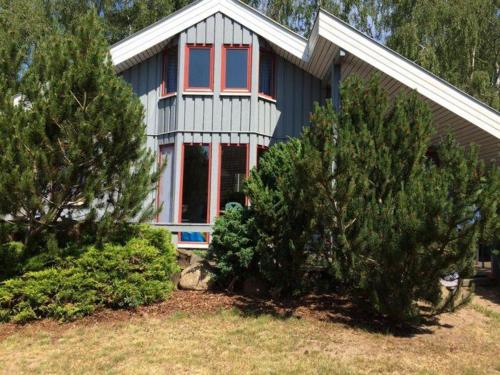 a house with red windows and trees in front of it at Wildgans 87 in Mirow