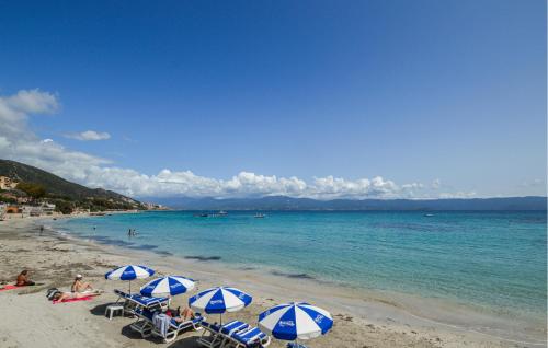 a beach with blue and white umbrellas and the ocean at 2 Bedroom Lovely Home In Piscia Rossa in Afa