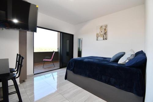 ein Schlafzimmer mit einem blauen Bett und einem TV in der Unterkunft Loft de lujo con 9 albercas y vistas al campo de golf in Mazatlán