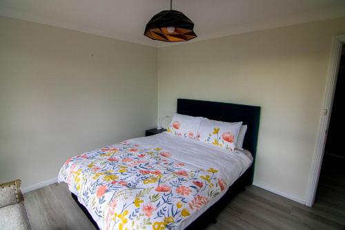 a bedroom with a bed with a floral comforter at Big quiet enclave amazing views in Wentworth Falls