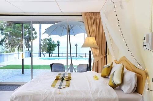 - une chambre avec un grand lit blanc et un parasol dans l'établissement Visas Seaview villa บ้านวิเศษ Pranburi, à Ban Pru Yai