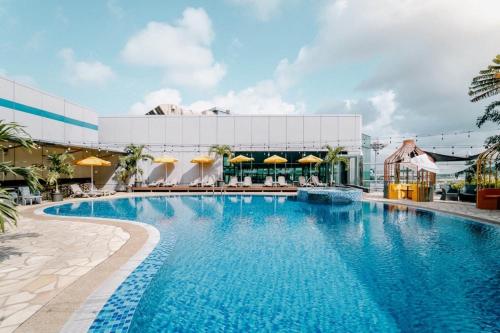 Aerotel Transit Hotel, Terminal 1 Airside في سنغافورة: وجود مسبح في الفندق مع الكراسي والمظلات