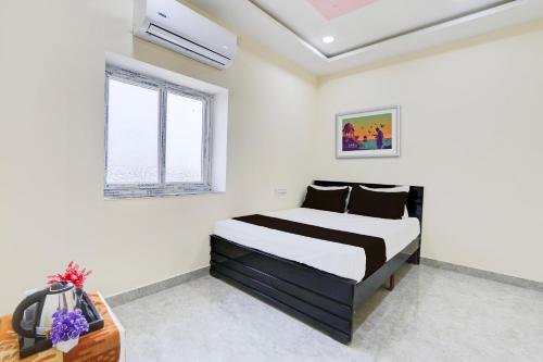 sypialnia z czarno-białym łóżkiem i oknem w obiekcie OYO NGS LODGE w mieście Hajdarabad