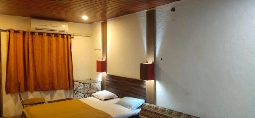 1 dormitorio con cama y cortina de color naranja en Hilltone Resort matheran, en Matheran