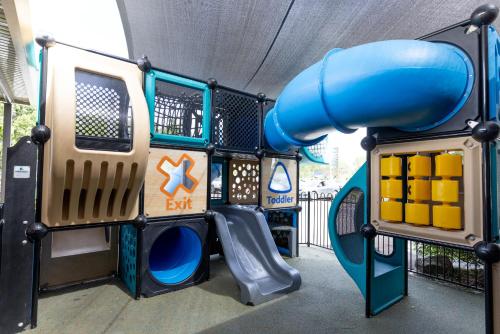 a playground with a blue slide in a building at Sundowner Hotel Motel in Caboolture