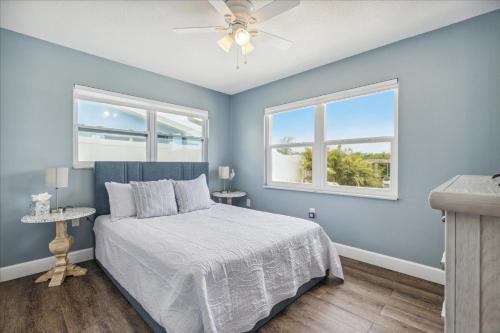 niebieska sypialnia z łóżkiem i dwoma oknami w obiekcie 106 La Riviere Rd w mieście Cocoa Beach