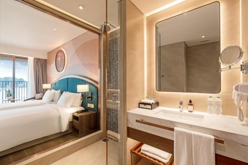 a bathroom with a bed and a sink and a mirror at Wyndham Garden Sonasea Van Don in Cái Rồng