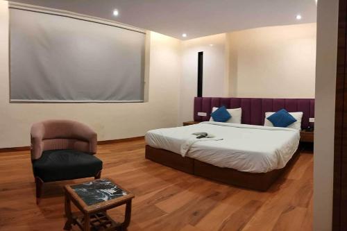 um quarto com uma cama grande e uma cadeira em Townhouse OAK Hotel Hardik Palace Sector 116 em Noida
