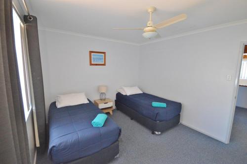 a room with two beds and a ceiling fan at Blue Ocean Villa 2 - Kalbarri WA in Kalbarri