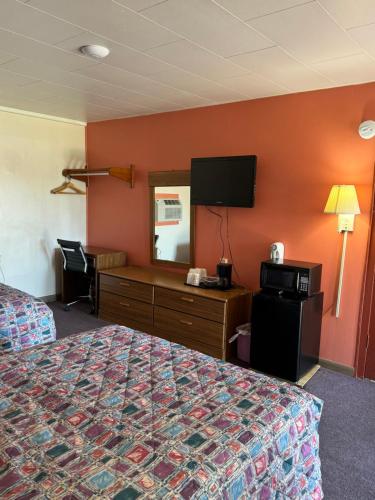 a hotel room with a bed and a tv on the wall at Budget Inn - Scottsboro in Scottsboro