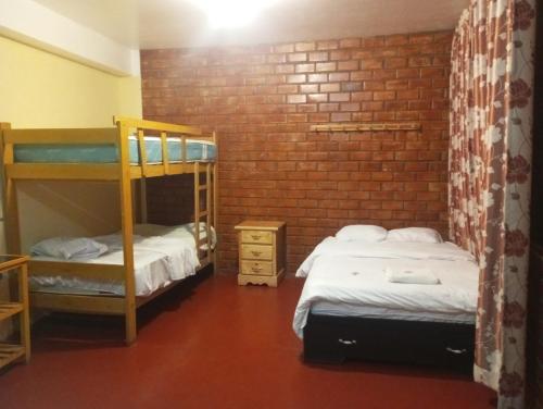 1 dormitorio con 2 literas y pared de ladrillo en ALOJAMIENTO PICSHA EXPEDITIONS, en Huaraz