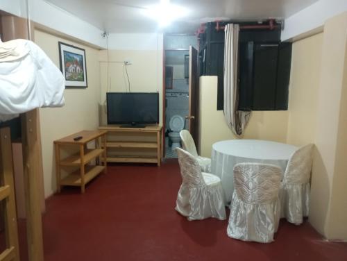 um quarto com uma mesa e cadeiras e uma televisão em ALOJAMIENTO PICSHA EXPEDITIONS em Huaraz