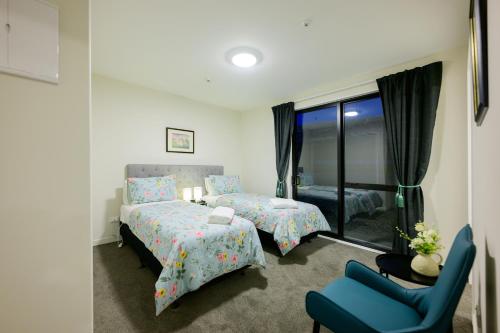 een slaapkamer met 2 bedden en een blauwe stoel bij Stargazing family apartment C in Lake Tekapo