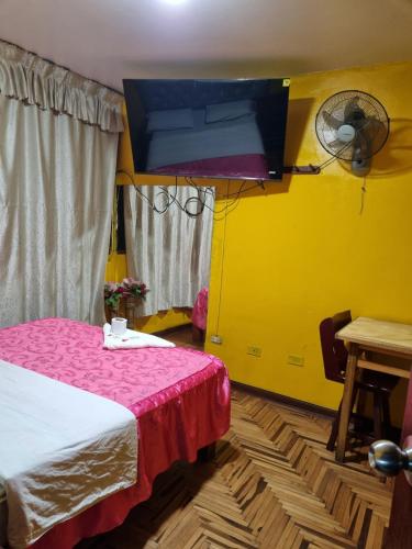 Habitación con cama y pared amarilla en Hostal Chavin, en Lima