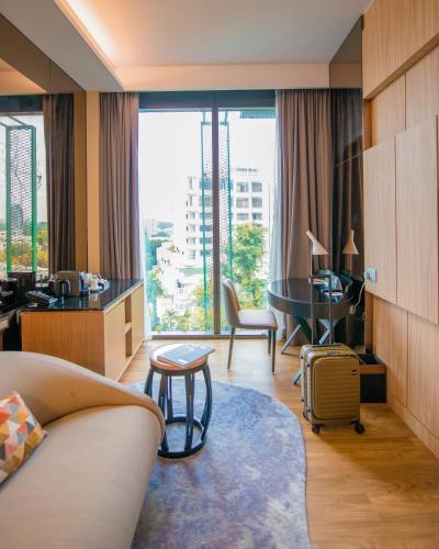 a hotel room with a couch and a desk and a table at Mercure Singapore On Stevens in Singapore