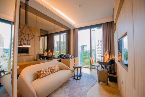 a living room with a couch and a large window at Mercure Singapore On Stevens in Singapore