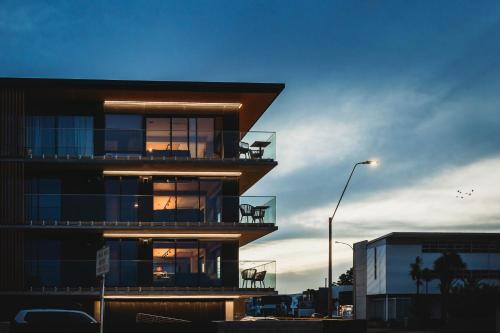 a building with chairs on the balcony at dusk at The Coomber - Apartments & Studios in New Plymouth