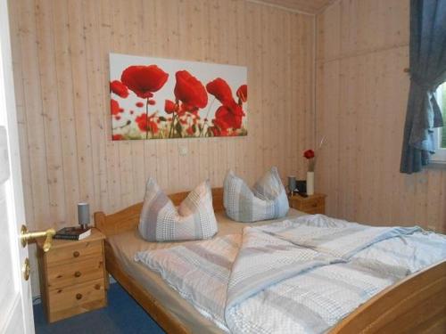 a bedroom with a bed with red flowers on the wall at Haubentaucher 80 in Rechlin