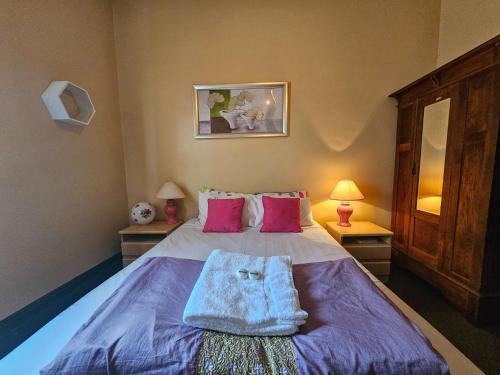 塞斯諾克的住宿－鈴鳥酒店，一间卧室配有一张带紫色床单和粉色枕头的床。