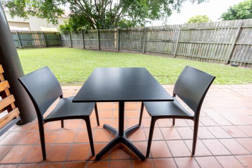a black table and two chairs on a patio at Sundowner Hotel Motel in Caboolture