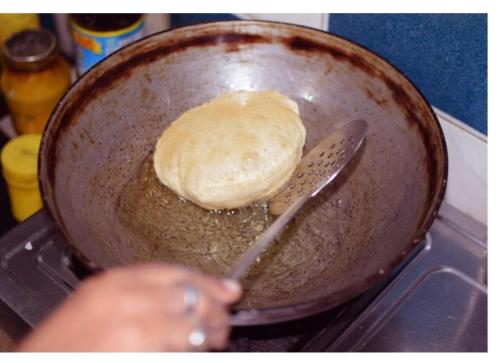 a person is holding a pan with a bread in it at SHREE HOME STAY in Dwārāhāt