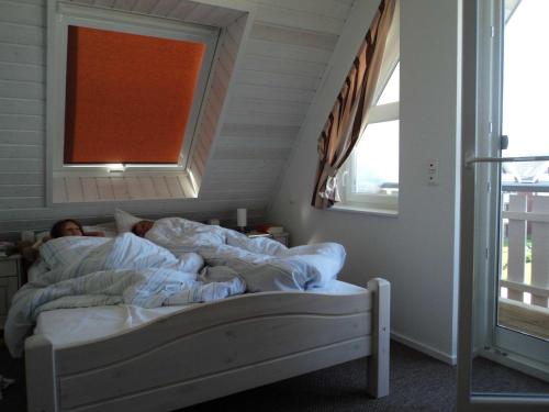 un hombre acostado en la cama en una habitación con ventana en Kapitänsdeck 475, en Zielow
