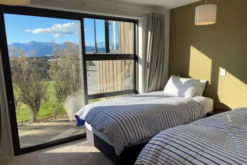two beds in a room with a large window at The Yellow Door in Wanaka