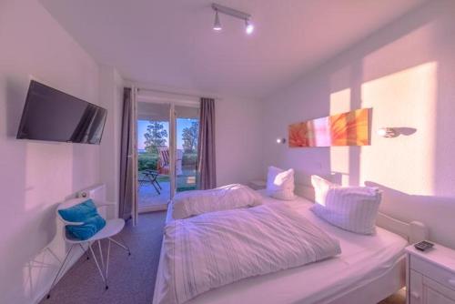 a white bedroom with a bed and a television at Gartendeck 531 in Rechlin