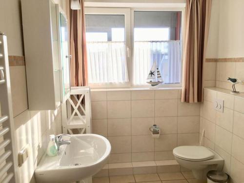 ein Badezimmer mit Waschbecken und Toilette und einem Fenster in der Unterkunft Mitteldeck 414 in Rechlin