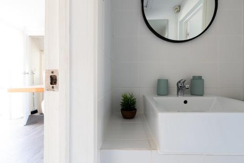 ein weißes Badezimmer mit einem Waschbecken und einem Spiegel in der Unterkunft Comfortable Urban Cottage with Parking in Launceston