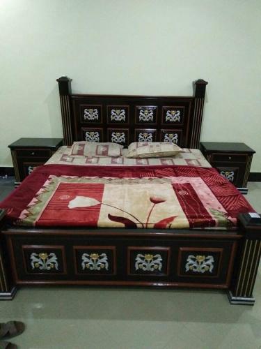 a bed with a red and white blanket on it at Glorious Guest House & Hotel in Multan
