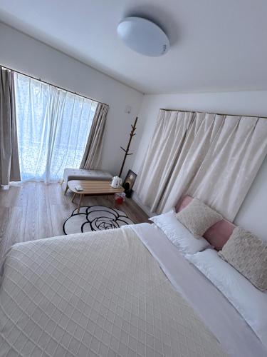 a bedroom with a large white bed and a couch at Sunflower 民泊 in Tokyo