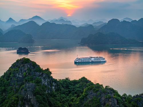 a boat on the water with mountains in the background at Indochine Cruise Lan Ha Bay in Ha Long