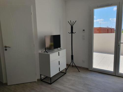 une chambre blanche avec une télévision et une commode avec une fenêtre dans l'établissement Studio cosy maison neuve Rodger, à Médis