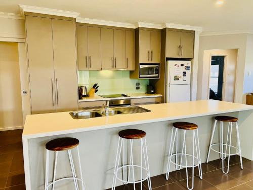 a kitchen with white cabinets and bar stools at Guichen Villa 3 - Wi-Fi Pets welcome outside in Robe