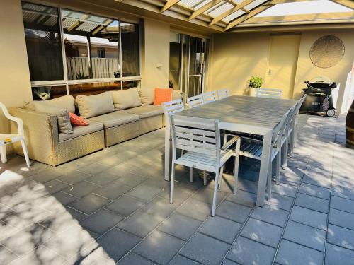 a patio with a table and chairs and a couch at Guichen Villa 3 - Wi-Fi Pets welcome outside in Robe