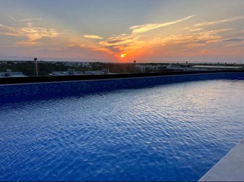a large swimming pool with a sunset in the background at Akua Tulum Mexico in Tulum
