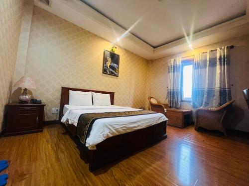a bedroom with a bed and a chair and a window at Khách Sạn Hoàng Anh Anh in Ho Chi Minh City