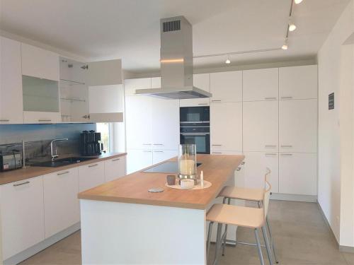 Una cocina con gabinetes blancos y una isla de madera con una silla. en Kondor 61, en Rechlin