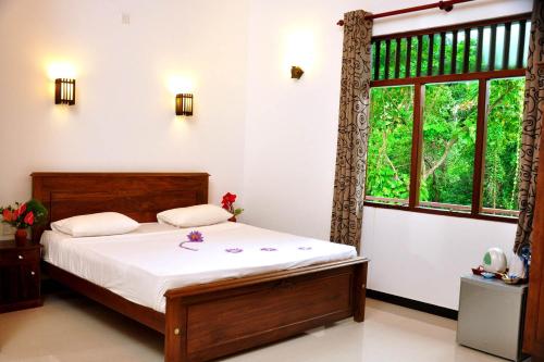 a bedroom with a bed and a window at Hannaford House Bentota in Bentota