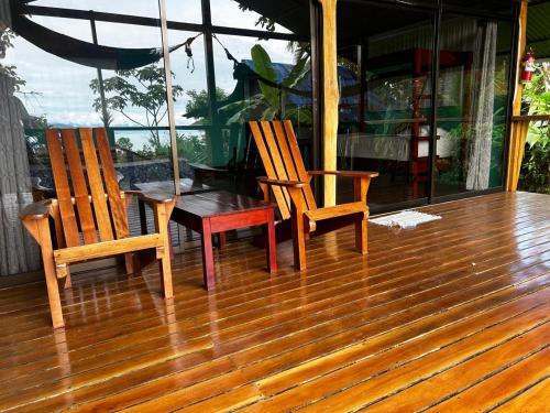 two chairs and a table on a wooden deck at Nativos Corcovado cabins in Drake